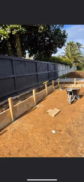 Timber garden bed being installed along a fence