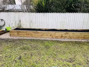 New timber raised garden bed beside a boundary fence