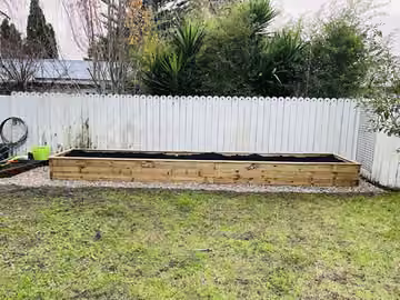Timber raised garden bed viewed along the fence