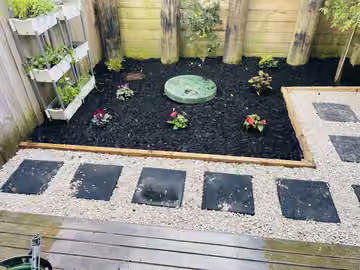 New plants, dark mulch and paths in a fenced courtyard garden